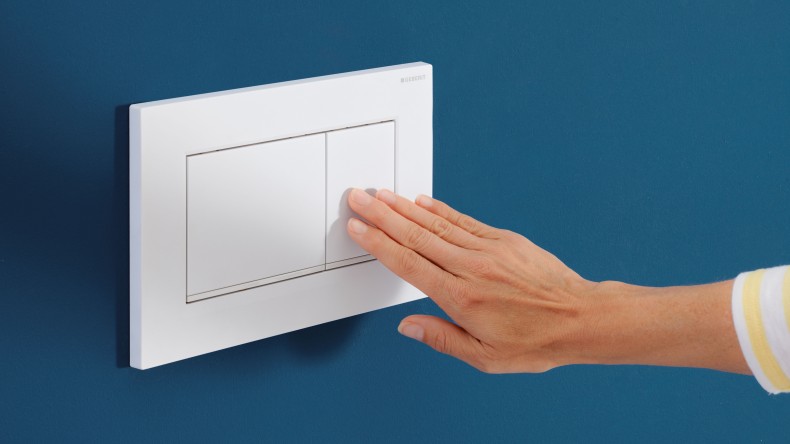 Hand löst auf der weissen Sigma20 Betätigungsplatte eine Spülung aus (© Geberit) Hand löst auf der weissen Sigma20 Betätigungsplatte eine Spülung aus (© Geberit)